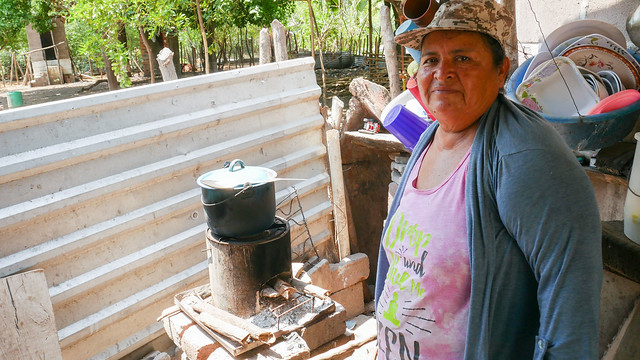 Petrona Cañénguez explica cómo cocina una sopa de frijoles en una de las cocinas eficientemente energéticas, conocidas como fogones rockets, en un habitáculo externo de su vivienda en la el caserío de San Sebastián El Chingo, uno de los beneficiados con un programa de desarrollo sostenible, en el municipio de San Luis La Herradura, en la costa del sur de El Salvador. Foto: Edgardo Ayala /IPS
