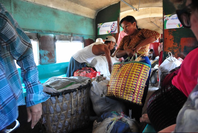 Una mujer carga bolsas de verduras en un vagón de tren en Yangón. Muchas personas usan ese medio de pasajeros pese a su lentitud para transportar productos que venden en poblados, pues no pueden costear el transporte por carretera. Crédito: Amantha Perera/IPS.