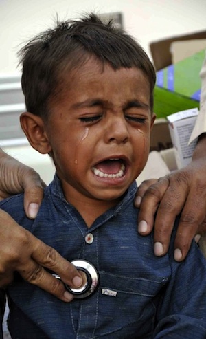 Un niño llora mientras se somete a un chequeo médico en un hospital improvisado. Los expertos dicen que los centros sanitarios en Tharparkar dejan mucho que desear. Crédito: Irfan Ahmed/IPS