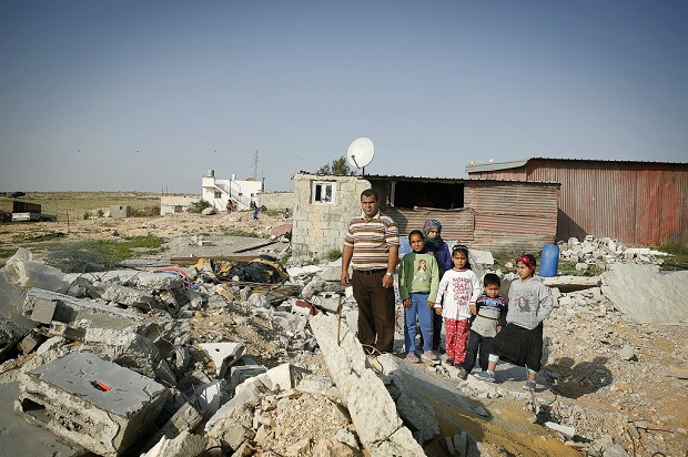 Naif Agele con sus hijos y sobrinos en las ruinas de la casa de su hermano, en una zona "no reconocida" de la localidad de Kuseife, en el desierto de Néguev. La vivienda fue demolida por las autoridades israelíes el 10 de marzo de 2014. Crédito: Silvia Boarini / IPS
