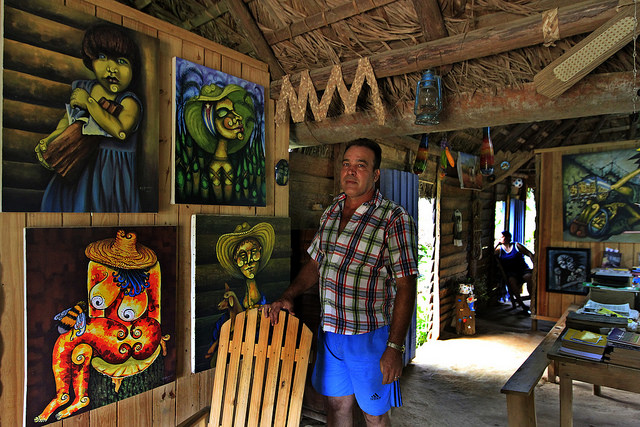 El pintor autodidacta Miguel Antonio Remedios en el interior de su casa rural, reconvertida en galería, estudio y muestra de casa rural tradicional, en El Abra, un caserío montañoso del municipio de La Palmaba, en la provincia de Pinar del Río, en Cuba. Crédito: Jorge Luis Baños/IPS
