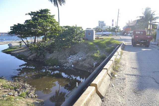 Desembocadura del Ñagá, un río de aguas oscuras y cauce estrecho por los vertidos industriales y la pérdida de sus manglares, en la costera ciudad de Bajos de Haina, en República Dominicana. Crédito: Dionny Matos/IPS