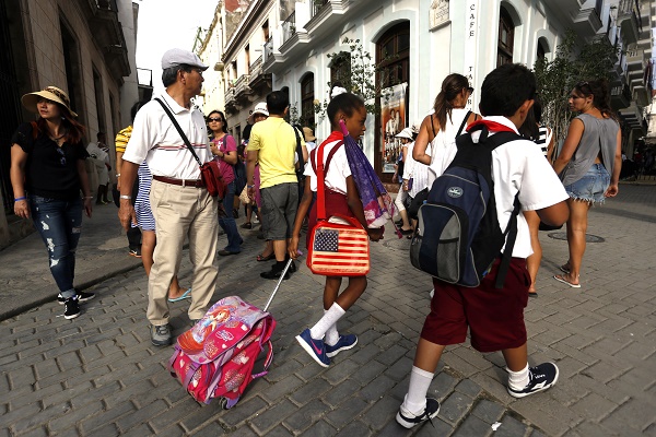 Dos estudiantes de la enseñanza primaria caminan próximo a un grupo de turistas extranjeros en una céntrica Plaza del centro histórico de La Habana Vieja, La Habana, Cuba. Crédito:Jorge Luis Baños/IPS.