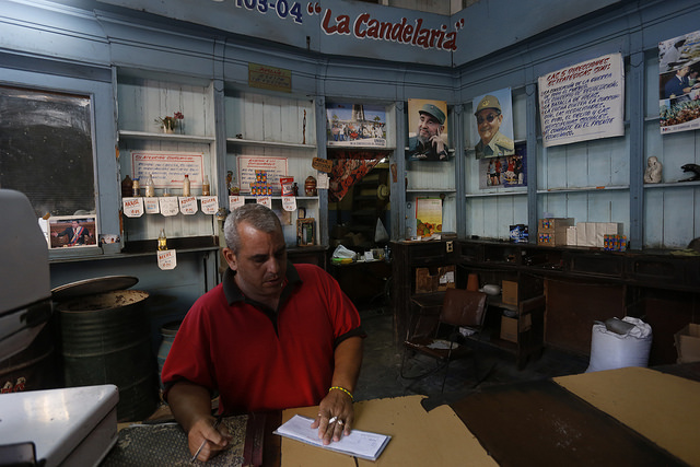 Un empleado permanece a la espera de clientes en el interior de una bodega estatal, que vende productos racionados, precariamente provisto, en un barrio de La Habana. Este tipo de negocios forman parte de un modelo en revisión en Cuba. Crédito: Jorge Luis Baños/IPS