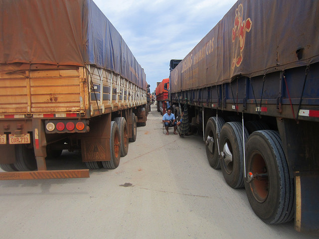 Dos choferes descansan mientras esperan a descargar sus camiones en el Complejo Agroindustrial Angostura (Caiasa), procesador de soja en Paraguay. Unos 2.000 camiones transportan la leguminosa hasta la planta, que en la época de zafra recibe en promedio 500 vehículos de gran tonelaje, cuya descarga no demora más de un día en las fechas más intensas. Crédito: Mario Osava/IPS