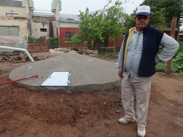 El campesino José Ramón Espinoza, al lado de una recién construida cisterna comunitaria para recoger el agua de lluvia, que permitirá a un grupo de familias mitigar las recurrentes sequías en Corzuela, un paraje rural de la norteña provincia de Chaco, en el norte de Argentina. El tanque subterráneo fue aportado por el Programa de Pequeñas Donaciones. Crédito: Fabiana Frayssinet/IPS