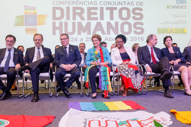 La presidenta Dilma Rousseff, sentada en el centro, con una flor en la mano que le acaba de ser entregada, durante la apertura de la Conferencia Nacional de Derechos Humanos, inaugurada el 27 de abril en Brasilia. En los actos de la mandataria de estos días se repiten los gestos de cariño con olor a despedida hacia la mandataria. Crédito: Roberto Stuckert Filho/PR