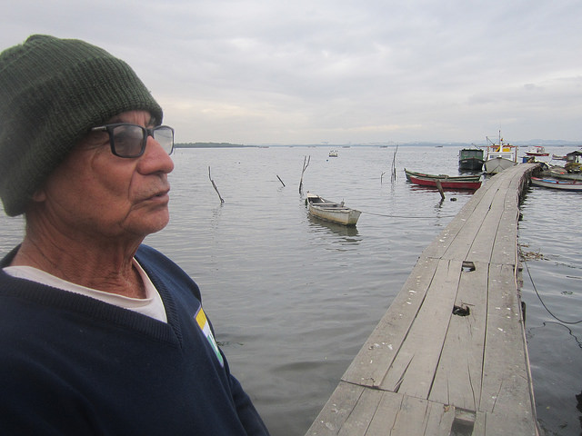 Sergio Souza dos Santos sobre el muelle que construyeron los pescadores de Tubiacanga, para adentrarse en la bahía de Guanabara, en la ciudad brasileña de Río de Janeiro, porque la sedimentación impide que sus embarcaciones se acerquen a la orilla, que hace décadas era una hermosa playa. Crédito: Mario Osava/IPS