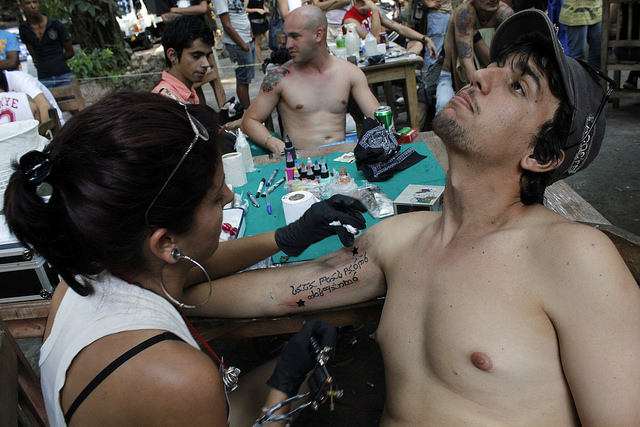 Una artista del tatuaje interviene el brazo de un joven durante el Festival Peace and Love, celebrado en Puentes Grandes, uno de los municipios que integran La Habana, en Cuba. Crédito: Jorge Luis Baños/IPS