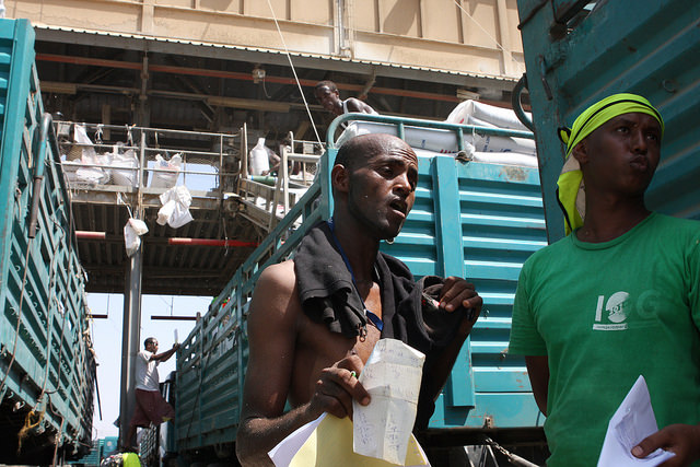 Los trabajadores portuarios aprovechan al máximo cualquier sombra que puedan encontrar entre los camiones cargados con asistencia alimentaria para Etiopía, agobiada por la sequía. Crédito: James Jeffrey/IPS.