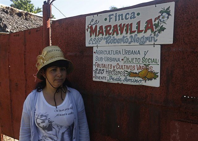 La agricultora Iraida Semino, ante la entrada a su finca La Maravilla, de la que es usufructuaria como se lee en el cartel en el portón. En Cuba, son aún pocas las mujeres que tienen acceso a la tierra y trabajan como productoras agropecuarias. Crédito: Jorge Luis Baños/IPS