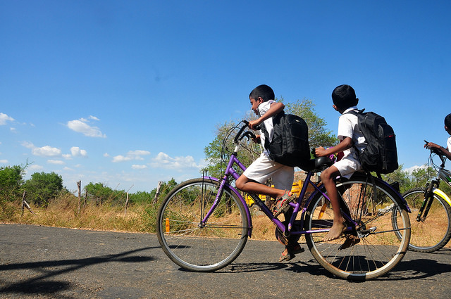 Niños se trasladan en bicicleta desde su casa a la escuela en Welikanda, en Sri Lanka, donde se instalaron muchas personas desde el final de la guerra civil en 2009. Crédito: Amantha Perera/IPS.