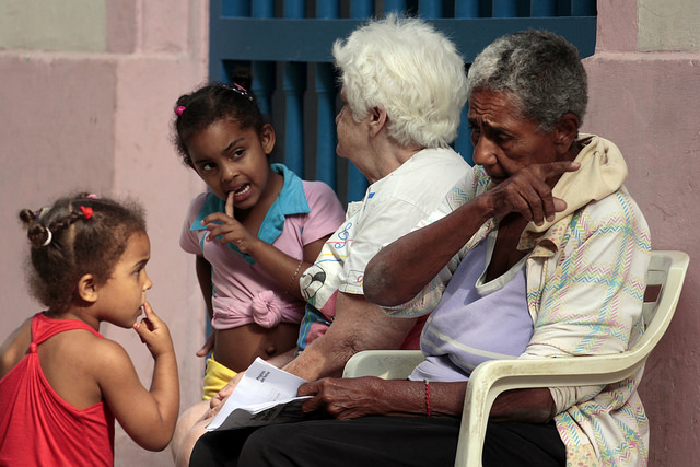 Dos abuelas con sus nietas a las que cuidan mientras sus madres trabajan, en una calle del casco histórico de la Habana Vieja, en Cuba. Los abuelos y abuelas trabajadores son incluidos en los beneficios de las nuevas normas para estimular la maternidad. Crédito: Jorge Luis Baños/IPS