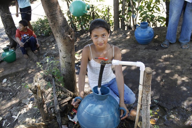 Una niña llena su cántaro de agua de la toma colectiva en la comunidad de Los Pinos, en el  occidente de El Salvador. Conexiones públicas y gratuitas como estas palían los problemas de acceso al agua en los hogares rurales que carecen de conexión por tuberías. Crédito: Edgardo Ayala/IPS