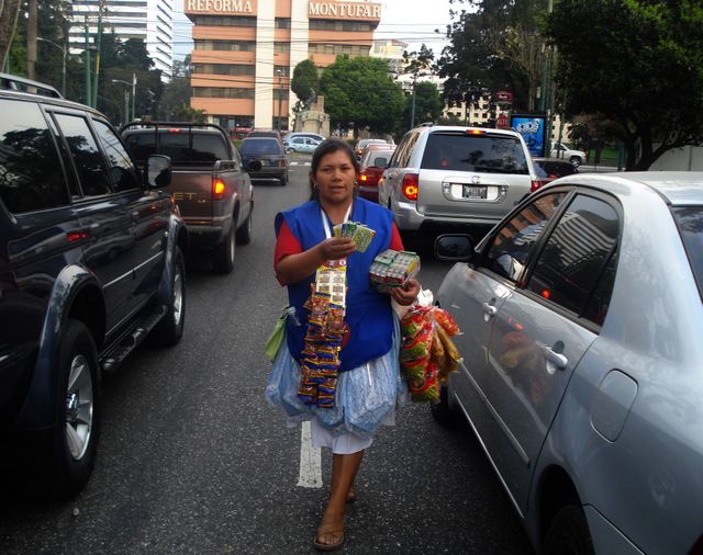 Una mujer vende golosinas entre los vehículos, en una de las calles de Ciudad de Guatemala. Crédito: Danilo Valladares/IPS