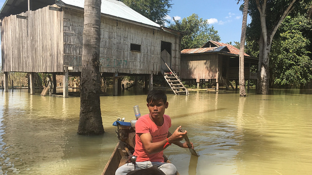 Un poblador de Kbal Romeas, en Camboya, rema entre dos casas semisumergidas. Crédito: Pascal Laureyn/IPS