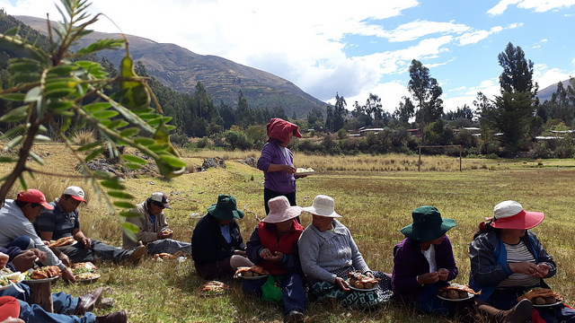 Mujeres y hombres de la comunidad de Paropucjio, en las alturas de los Andes peruanos, en la región de Cusco, comparten el almuerzo preparado tras terminar la faena comunitaria de construir uno de los 80 pequeños invernaderos, en los que un número igual de mujeres podrá cultivar vegetales orgánicos pese a las temperaturas extremas de la zona. Crédito: Mariela Jara/IPS 