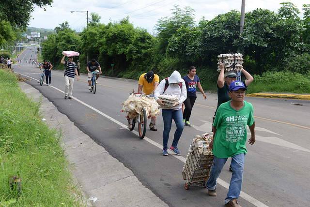 Personas caminan con productos para vender o que han adquirido, en la carretera entre Managua y Masaya, distantes 29 kilómetros. Los bloqueos en las vías y la falta de transporte público en Nicaragua, debido a las protestas, obligan a la población a recorrer a pie largas distancias. Crédito: Manuel Esquivel/IPS