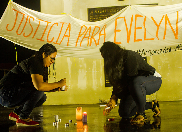 Dos mujeres prenden velas ante el monumento a la Constitución, en la capital de El Salvador, durante una manifestación de protesta por la condena a una joven mujer a 30 años de cárcel, acusada de haberse practicado un aborto. Crédito: Edgardo Ayala/IPS