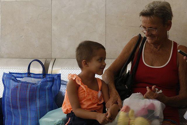 Suelen Suárez, de tres años, y su abuela Milagros Miranda, residentes en un municipio cercano a La Habana, mientras dialogan con IPS en un corredor del Instituto Nacional de Oncología y Radiobiología de El Vedado, en la capital cubana, donde la niña es tratada de un tumor. Crédito: Jorge Luis Baños/IPS