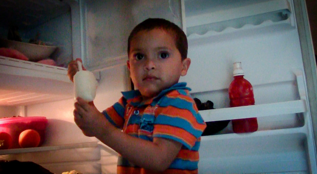 Un niño de La Joya, un caserío del este de El Salvador, mientras toma una charamusca, un helado a base de frutas, del refrigerador de Lilian Gómez, que gracias a la llegada de la electricidad ha montado un pequeño negocio de elaboración de estos productos, ya populares entre sus vecinos. Crédito: Edgardo Ayala/IPS