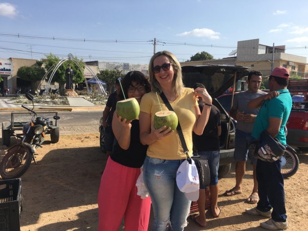 Dos participantes en el encuentro internacional de periodistas toman agua de coco en la feria de la ciudad de Sousa, donde se venden directamente al consumidor una gran variedad de frutas y hortalizas producidas por agricultores familiares de la zona, en el estado de Paraíba, en el Nordeste de Brasil. Crédito: Orlando Milesi/IPS