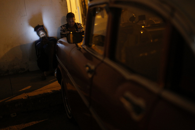A la luz de las pantallas de sus celulares y los faros de un vehículo, dos jóvenes cubanos acceden a Internet a través de una red inalámbrica en el barrio de La Víbora, en el municipio de Diez de Octubre, en La Habana. Crédito: Jorge Luis Baños/IPS