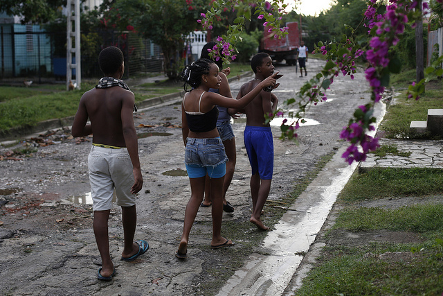Un grupo de adolescentes camina por una calle mal asfaltada y con algunos pozos dejados por la lluvia, en el barrio Nuevo Vista Alegre, uno de los afectados por el déficit del servicio de alcantarillado en Santiago de Cuba, la segunda ciudad del país, por detrás de La Habana. Crédito: Jorge Luis Baños/IPS