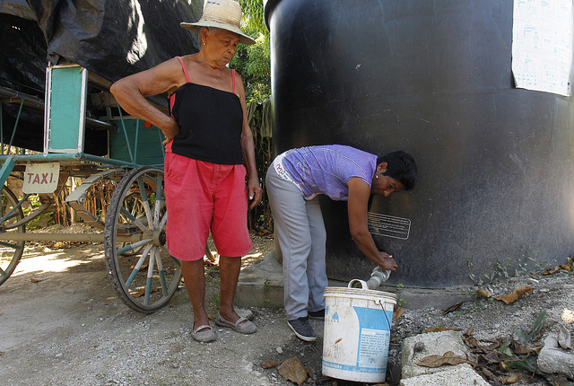 La concejala Magalis Benítez, de pie, es responsable de un tanque comunitario de agua potable, que abastece a las familias del barrio periférico El Congrís, en el municipio Palma Soriano, colindante con la segunda ciudad del país, Santiago de Cuba, en el este del país. Crédito: Jorge Luis Baños/IPS