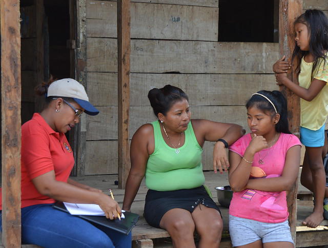 Una de las encuestadoras entrevista a una mujer indígena, mientras dos hijas observan, en la entrada de una vivienda de la comarca emberá. Crédito: FAO Mesoamérica