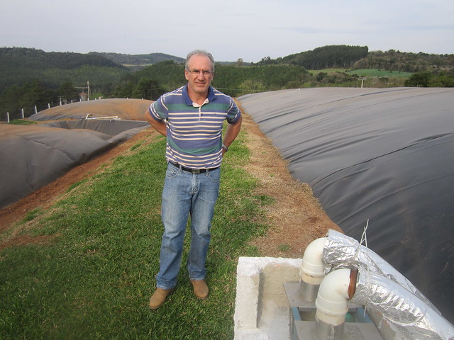 El porcicultor Anélio Thomazzoni entre los tres biodigestores con los que actualmente produce el biogás para la generación de 280.000 kilovatios/hora en su granja, en el pequeño municipio de Vargeão, en el sur de Brasil. Parte del biocombustile se purificará para transformarlo en biometano, mientras se instalan 6.000 metros cuadrados de placas fotovoltaicas para generar 130.000 kilovatios/hora. Crédito: Mario Osava/IPS