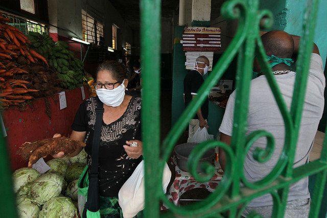 Una mujer, con una mascarilla de protección, abandona un mercado agropecuario con los productos frescos recién adquiridos, en un barrio de La Habana, en Cuba. Foto: Jorge Luis Baños/IPS