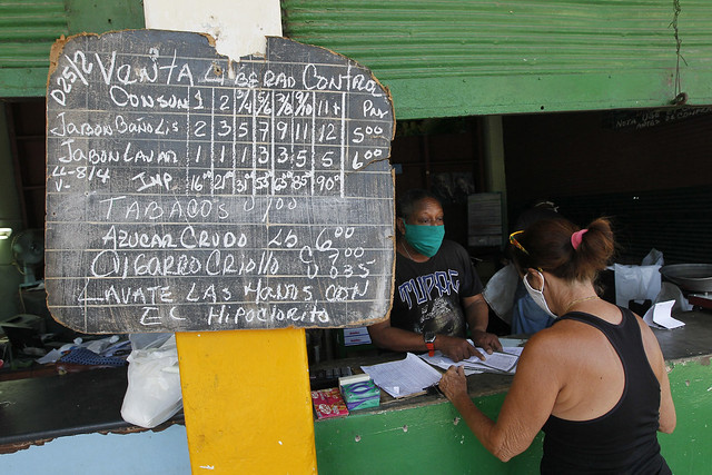 Un empleado despacha a una clienta productos racionados a precios subsidiados, incluidos en la libreta de abastecimiento cubana, en una desvencijada bodega del municipio de Playa, en La Habana. Foto: Jorge Luis Baños/IPS