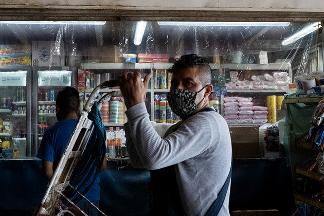 Un acarreador pasa frente a una tienda de comestibles protegida con plástico al final de uno de los pasillos del mercado. Foto: María Ruiz/Pie de Página