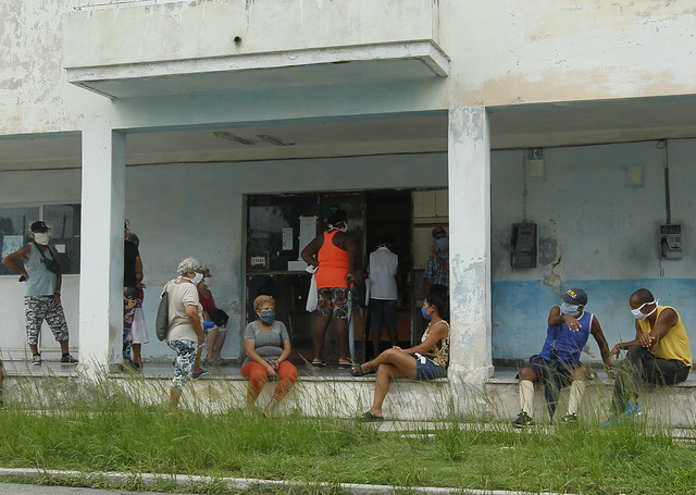 Clientes mantienen la distancia y usan mascarillas protectoras para prevenir el contagio de la enfermedad covid-19 mientras aguardan en el exterior de una farmacia para adquirir medicamentos, en el municipio de 10 de Octubre de La Habana, en Cuba. Foto: Jorge Luis Baños/IPS