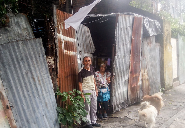 Los vendedores ambulantes René Murgas, de 60 años, y Lucía Cortez, de 73 años, residentes en un precario habitáculo en el sur de San Salvador, se sumaron a las familias que colocaron una bandera blanca fuera de su hogar para indicar su carencia de comida. Y en su caso tuvieron suerte, porque recibieron un paquete de alimentos del gobierno, con espaguetis, aceite, leche en polvo y siete latas de atún. Foto: Edgardo Ayala/IPS