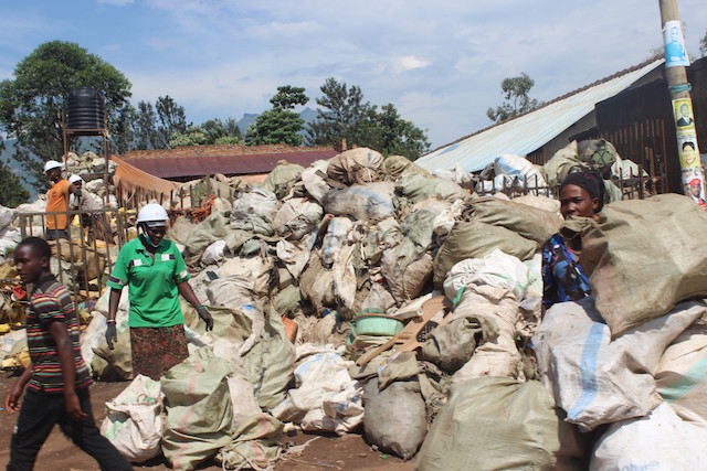 Dos mujeres y algunos hombres recolectan desechos para su reutilización en un basurero al aire libre en Mbale, una ciudad del este de Uganda. El uso ecológico de desechos plásticos o de neumáticos se considera más ecológico que su eliminación o reducción. Foto: Wambi Michael / IPS