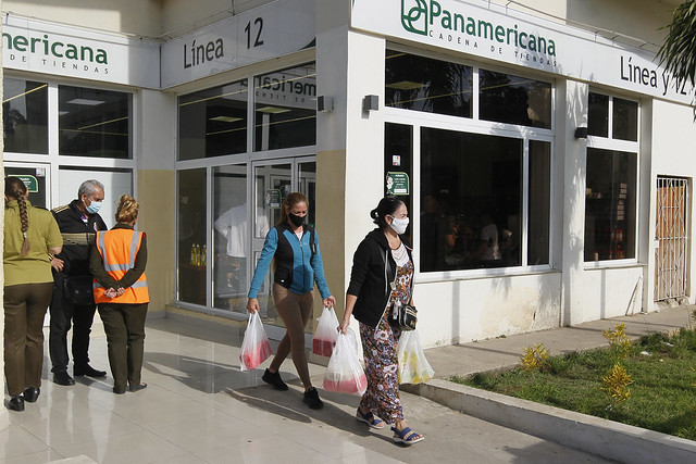 Clientes salen con sus compras de una tienda que vende productos comercializados en moneda convertible, en el barrio del Vedado, en La Habana. El inmueble fue objeto en días recientes de acciones vandálicas contra sus vidrieras por parte de personas, que según la posición del gobierno de Cuba intentan crear un clima de inestabilidad social. Foto: Jorge Luis Baños/IPS