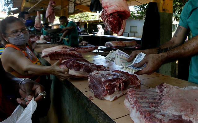 Una clienta señala un corte de carne mientras detrás del mostrador un empleado sostiene un fajo de billetes en CUP y CUC, en un mercado privado de Boyeros, uno de los municipios de La Habana. Desde el 1 de enero, en Cuba circulará únicamente el peso cubano (CUP), con una tasa de cambio de 24 unidades por dólar. Foto: Jorge Luis Baños/IPS
