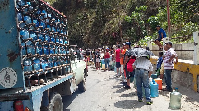 La escasez de agua en Caracas continúa forzando a habitantes de las barriadas populares a formar largas filas para llenar unos pocos bidones en algunas tomas a orillas de las vías. Comprar agua de garrafones resulta cada vez más costoso en medio de la profunda crisis socioeconómica en que está hundida Venezuela. Foto: Humberto Márquez /IPS