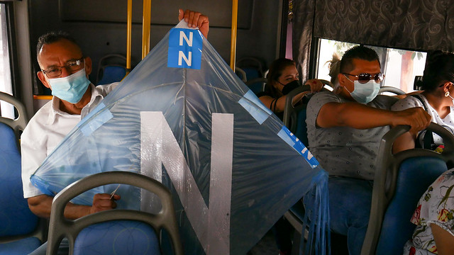 Francisco Reyes, de 61 años, vuelve a su casa en un autobús colectivo, luego de votar por el llamado bukelismo, como lo evidencia la cometa que lleva consigo, con los colores de azul cian del del partido del presidente Nayib Bukele y su partido, Nuevas Ideas. Foto: Edgardo Ayala / IPS